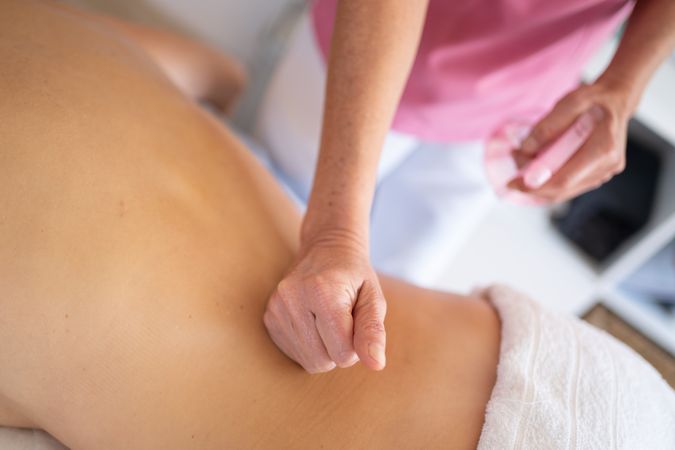 Masseuse massaging lower back of woman in spa salon