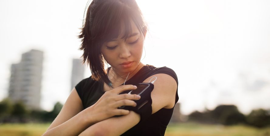 Close up of young woman checking her smartphone while exercising