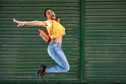 Side view of happy female with short hair jumping in casual clothes