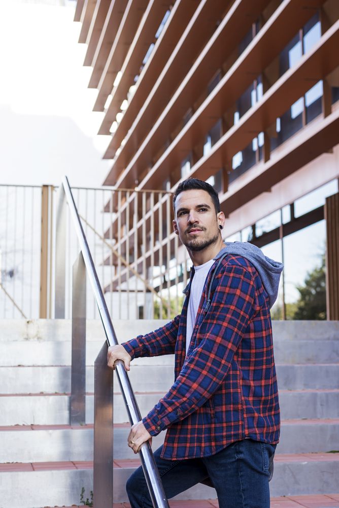 Man in plaid shirt walking up stairs on a sunny day