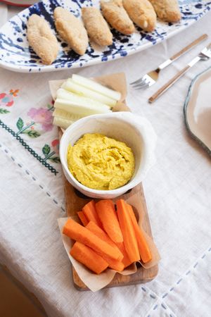 Fresh carrots and cucumber with hummus dip set on casual table