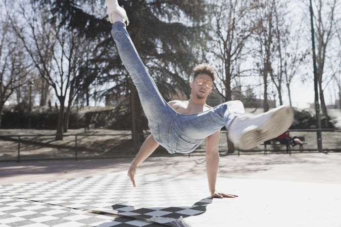 Shirtless man dancing break dance in park