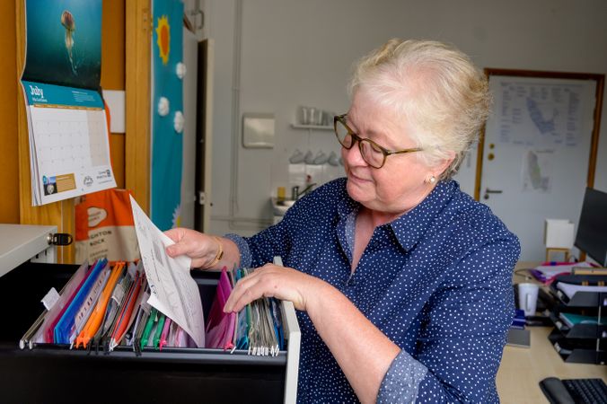 Mature woman looking at paper files in an office