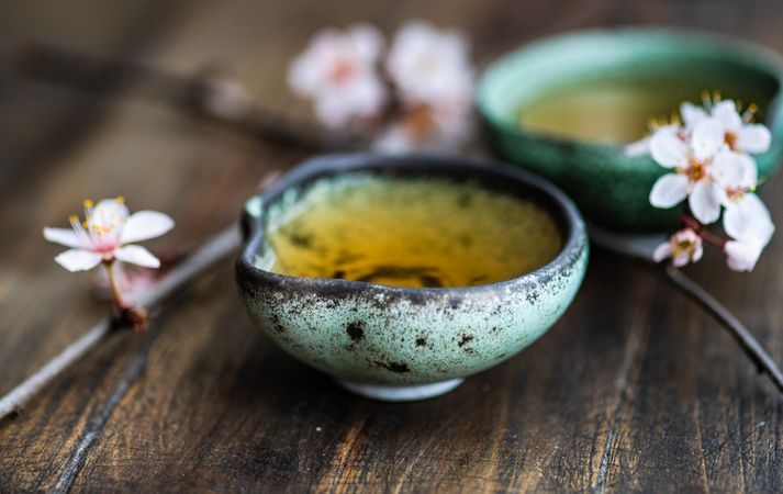 Green tea set and blooming peach tree branch on wooden table