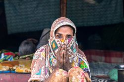 Distressed woman wearing headscarf sitting on floor outdoor