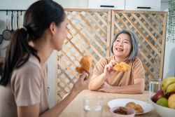 Mature mother and adult daughter enjoying croissants at home