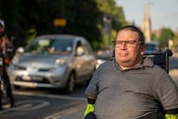 Man sitting in wheelchair on sidewalk in busy city