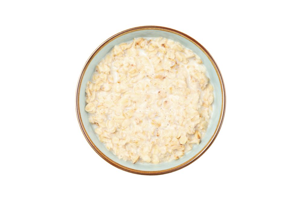 Bowl with cooked oatmeal isolated on plain background