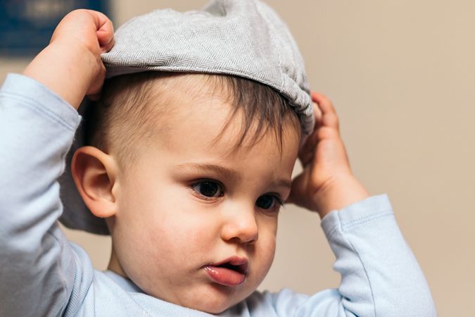 cute baby putting on a hat at home