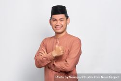 Happy Muslim man in kufi hat making thumbs up gesture with hand 4MyYa4
