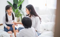 Asian mother playing with two kids in bedroom at home