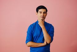 Medium shot of Latino man in pink studio with hand on chin