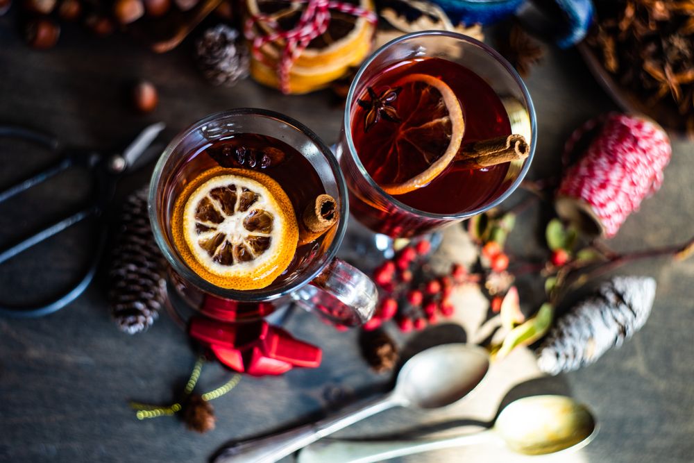 Dried orange slices and cinnamon sticks in mugs of warm wintry drinks