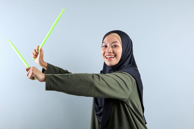 A Hijabi Woman  doing Pound Fit Workout with Green Stick