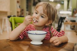 Girl eating with hand from white bowl