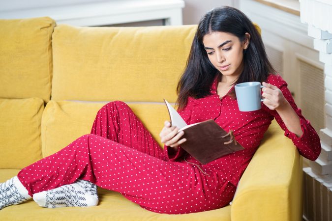 Female relaxing in red pajamas at home with book
