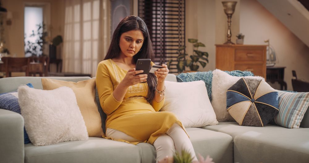 Portrait of Indian Woman Utilizing Smartphone and Credit Card for Online Purshases at Home