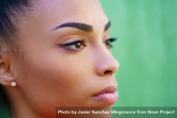 Side portrait of Black female in front of green background 5qjya4