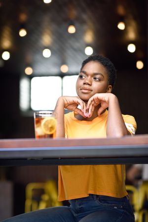 Contemplative female sitting with ice tea at counter of modern cafe