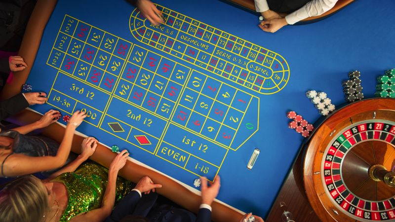 Top Down View Of Successful Men and Women Partying in a Luxurious Casino. Young People Gambling at a Roulette Table, Putting High Stakes Bets. Entertainment Industry and Glamorous Lifestyle Concept.