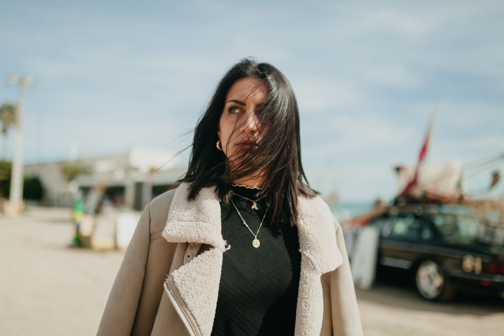 Stylish woman with jacket on beach parking