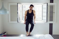 Young happy man sitting on window
