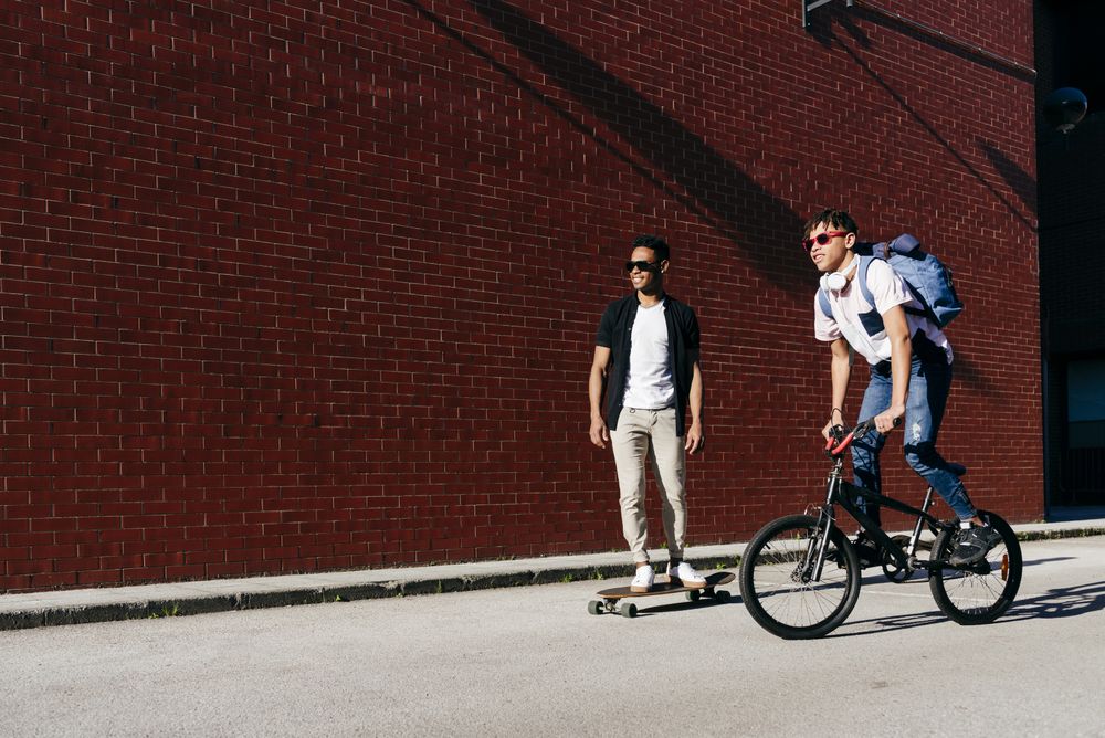 Young Black men riding bicycle and skateboard