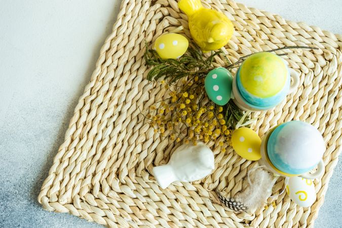 Top view of Easter table setting with with bird ornament and decorative eggs in cups