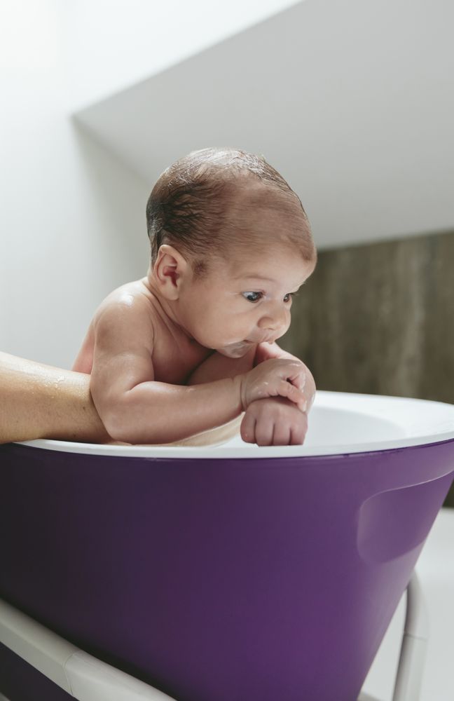 Newborn in the bathtub held by her mother