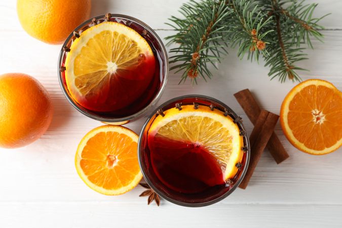 Glasses of tasty mulled wine with orange on wooden background, top view