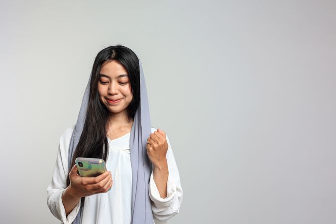 Indonesian Female with Veil Happy Using Mobile Phone, Excited Smile.