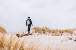 Man walking between sand field with dry grass
