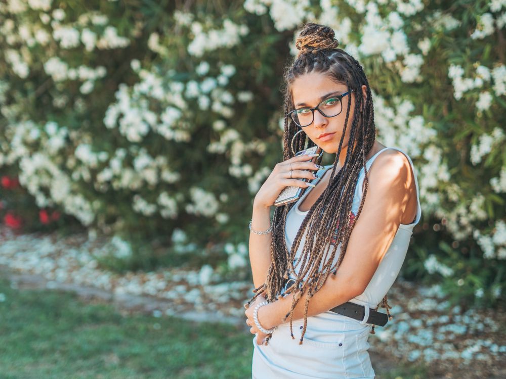 Trendy young female using mobile phone outside