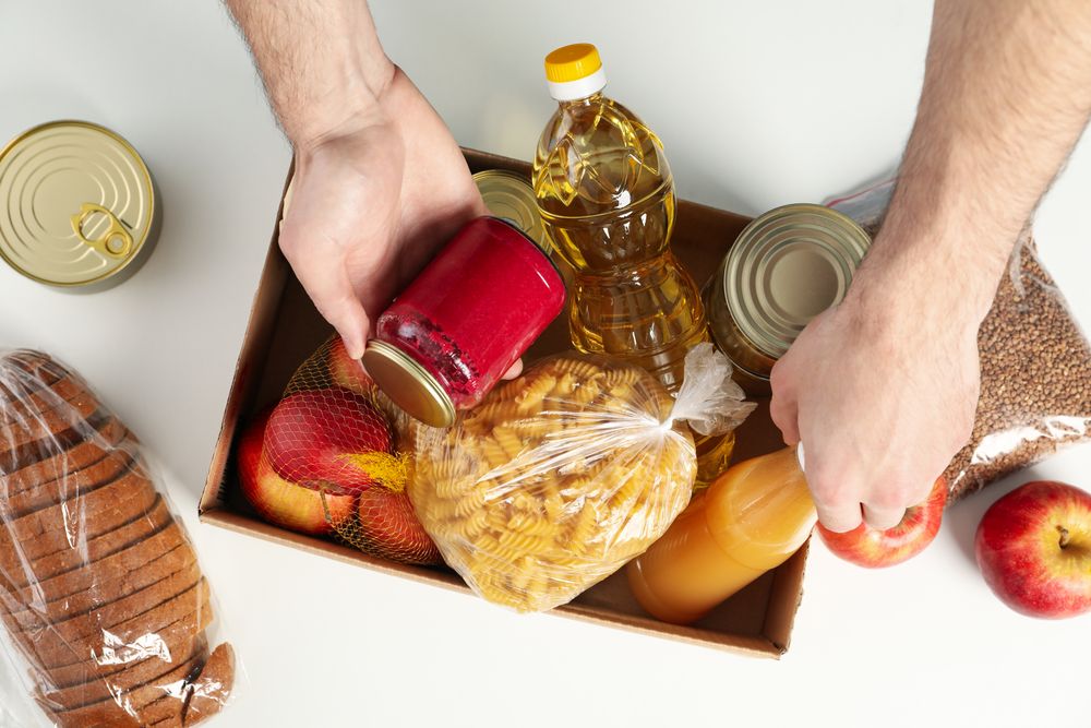 Young man puts groceries in donation box. Volunteer