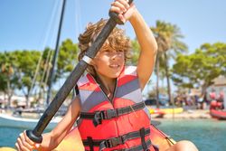 Carefree child rowing kayak in ocean on summer day