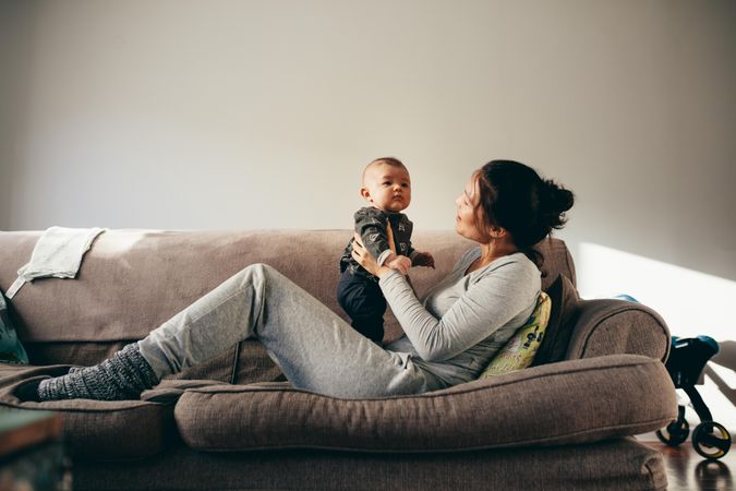 Young mother talking with her baby while relaxing on a couch