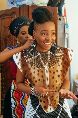Mom of young Zulu bride putting beaded necklace on adult daughter
