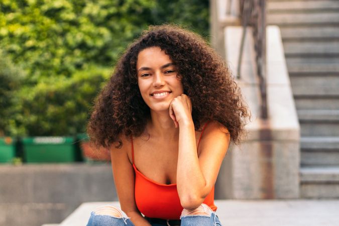 young female with curly hair portrait sitting on a stairs