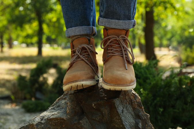 Woman in jeans and boots standing on rock outdoor, close up