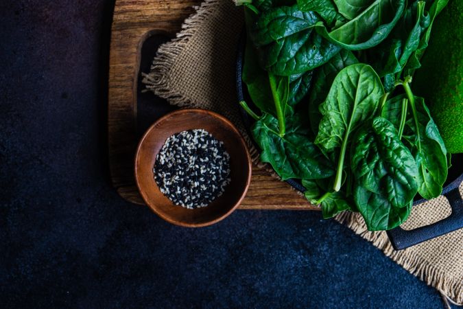 Fresh spinach on board with bowl of seasonings
