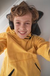 Cheerful child in headphones listening to music and taking selfi