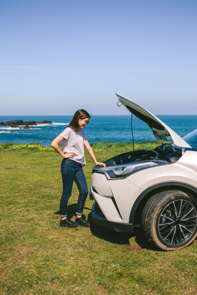 Woman looking engine of broken down car