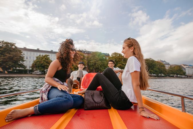 Two young women on pedal boat on river in the city