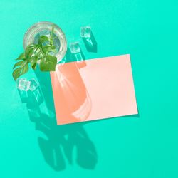 Tropical cocktail with ice cubes and pink paper card note on vivid blue background
