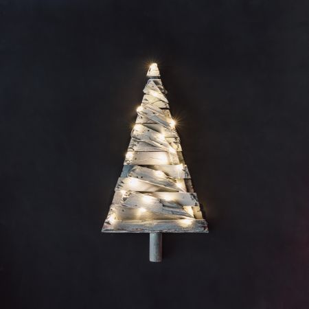 Christmas tree made of planks of wood with lights on dark background