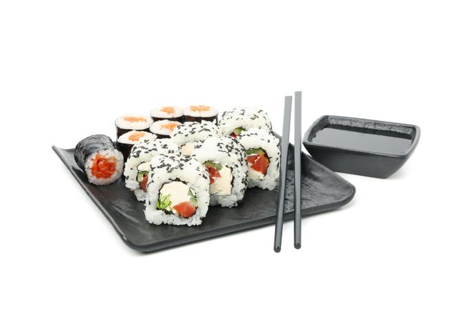 Tray with sushi rolls, chopsticks and soy sauce isolated on light background