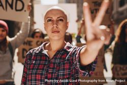 Bald woman protesting outdoors and showing a peace hand sign 4Zp610