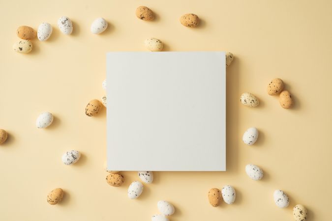 Easter eggs on pastel yellow background with paper card note