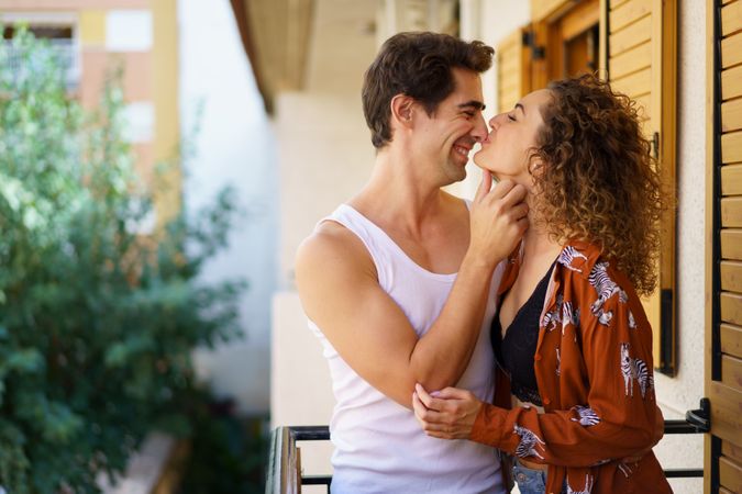 Romantic young couple caressing on balcony of modern building