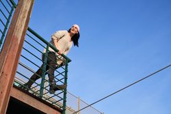 Cheerful woman in pink scarf leaning on metal fence